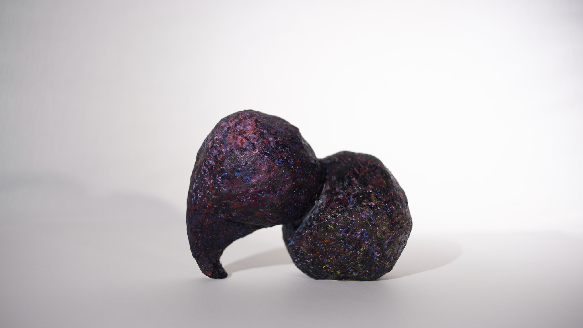 Small plaster sculpture in dark multicolor layers by artist Carrie Ruddick.